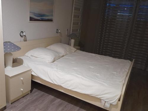 une chambre avec un lit avec des draps blancs et une lampe dans l'établissement ACAPULCO 86&87, aux Issambres