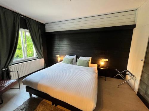 a bedroom with a large bed and two windows at La Villa Blanche Spa in Spa