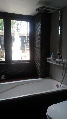 a bathroom with a window and a tub and a toilet at The Dream Home Villas in Denpasar