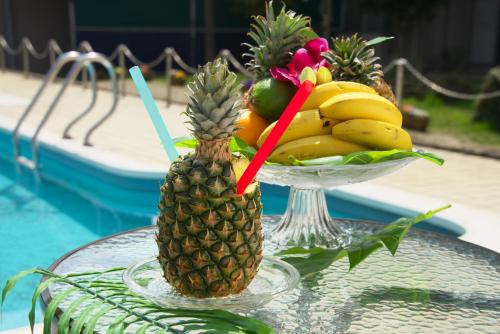 a bowl of fruit on a glass table next to a pineapple at Hyper Resort Villa Shionoe in Shionoe