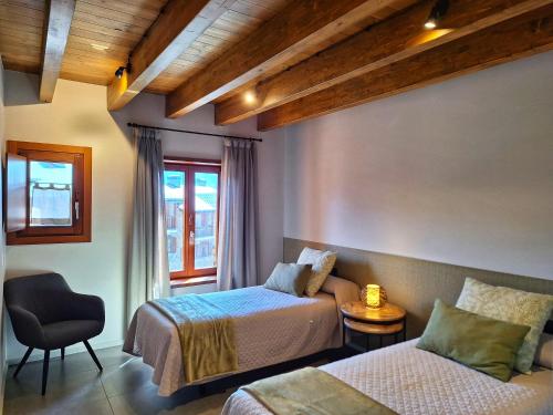 a bedroom with two beds and a chair and a window at Apartament "Enclau" Turismo Rural Cal Rialla in Llivia