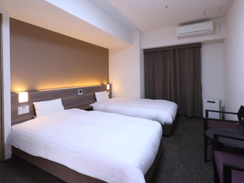 two beds in a hotel room with white sheets at Dormy Inn Premium Nagoya Sakae in Nagoya