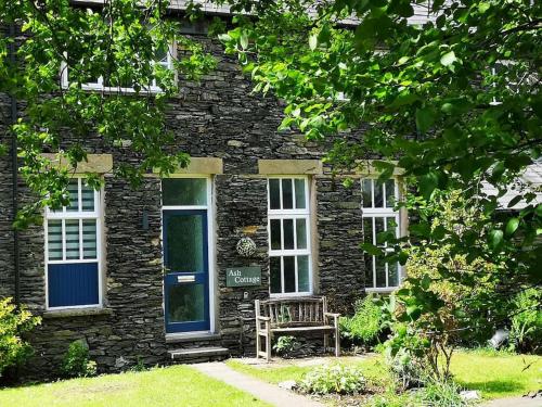 a stone house with a bench in front of it at Ash Cottage in Windermere