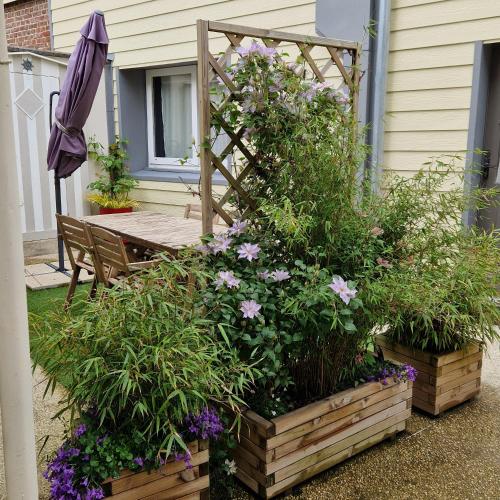 a patio with a table and some flowers and an umbrella at Halte Nature en Baie de Somme in Saint-Valery-sur-Somme