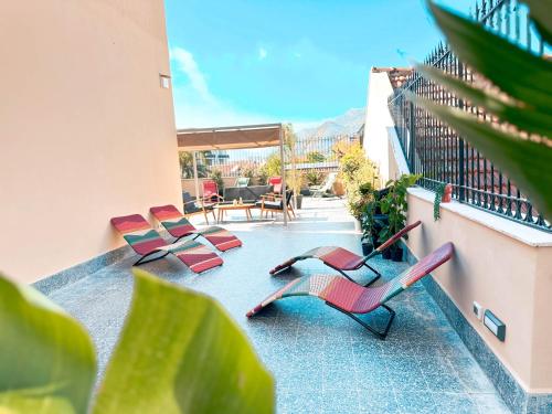 a balcony with pink chairs and a table and chairs at Ostello Bello Palermo in Palermo