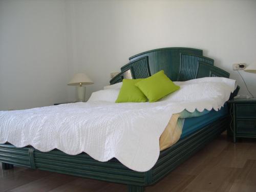 a green bed with white sheets and green pillows at APT EL FARO ARKADIA BEACH MIJAS COSTA Marvellous Frontbeach with stunning seaviews and historic lighthouse in Mijas Costa