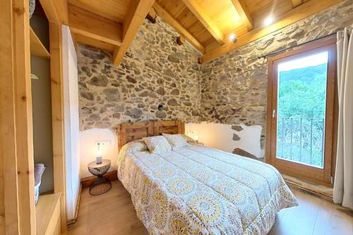 a bedroom with a bed and a stone wall at Cal Cumell, Allotjament turístic in Aransá