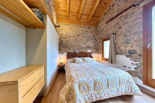 a bedroom with a bed and a stone wall at Cal Cumell, Allotjament turístic in Aransá