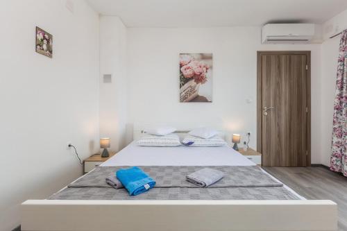 a white bedroom with a bed with blue pillows on it at Apartmani Tena in Njivice