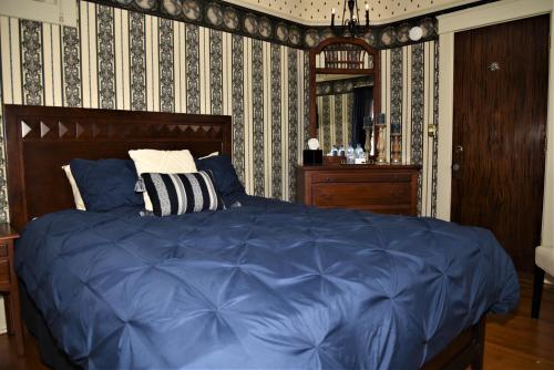a bedroom with a bed with blue sheets and wallpaper at Grand Colonial Bed and Breakfast in Herkimer