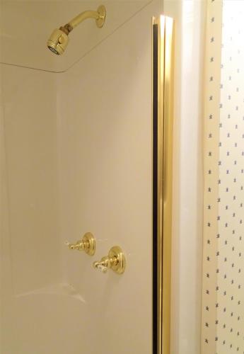 a shower with a glass door with a gold handle at Grand Colonial Bed and Breakfast in Herkimer