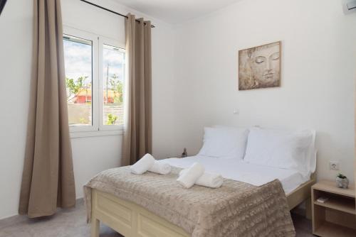 a bedroom with a bed with white sheets and a window at Dimitras Home in Lefkímmi