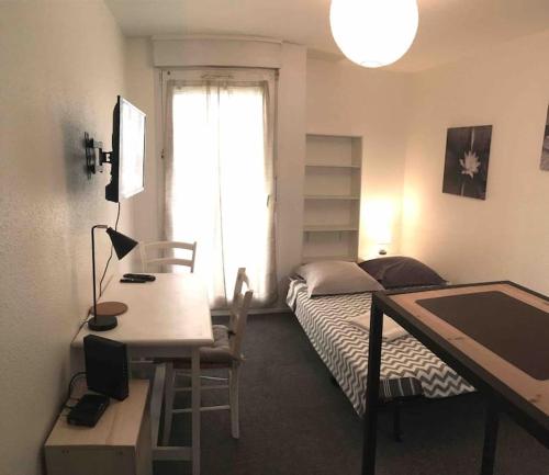 a bedroom with a bed and a desk and a window at Studio NÉNUPHAR in Chambéry