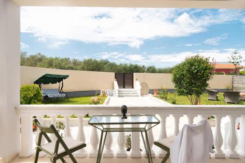 a white balcony with a glass table and chairs at Dimitras Home in Lefkímmi