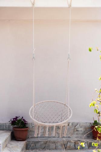 a swinging chair in a porch with plants at Dimitras Home in Lefkímmi