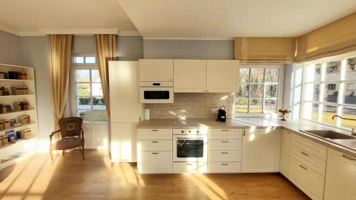 a kitchen with white cabinets and a sink at Schieszl Villa in Zamárdi