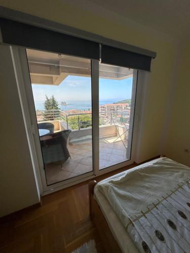 1 dormitorio con ventana y vistas a un balcón en Blue Sky Apartment, en Petrovac na Moru