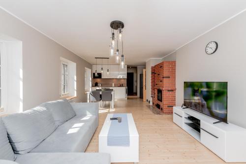 a living room with a white couch and a tv at Vingi Familyhouse with free parking and sauna in Pärnu