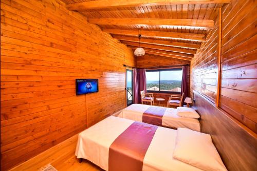 two beds in a room with wooden walls at Zūhre Cafe Bungalow in Demre