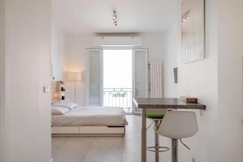 une chambre blanche avec un lit et un bureau dans l'établissement Beau Studio Le Grand Palais 100m des plages, à Juan-les-Pins