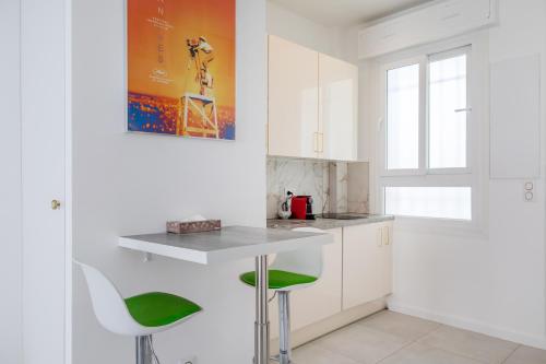 une cuisine avec des placards blancs et des tabourets verts dans l'établissement Beau Studio Le Grand Palais 100m des plages, à Juan-les-Pins