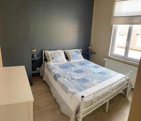 une chambre avec un lit avec une couette bleue et une fenêtre dans l'établissement la jolythalys, à Étaples
