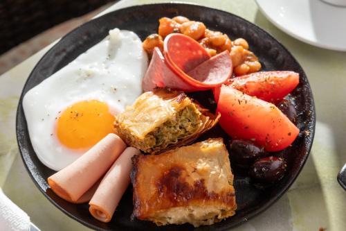 a plate of breakfast food with eggs sausage and fruit at Bella Vista Beach Hotel in Benitses