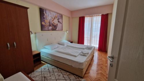 1 dormitorio con 1 cama y una ventana con cortinas rojas en Adeona Apartments, en Ohrid