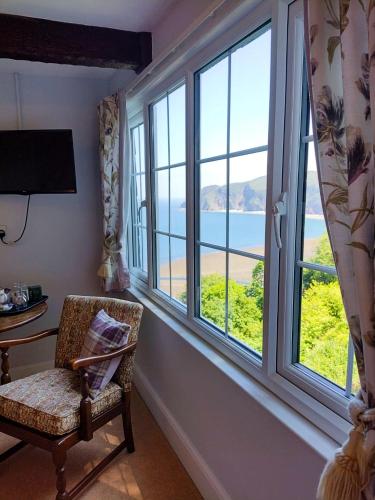 a room with a chair and a window with a view at Chough's Nest Hotel in Lynton