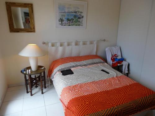 une chambre avec un lit et une table avec une lampe dans l'établissement Parc de Diane ANTIBES RDJ, à Antibes