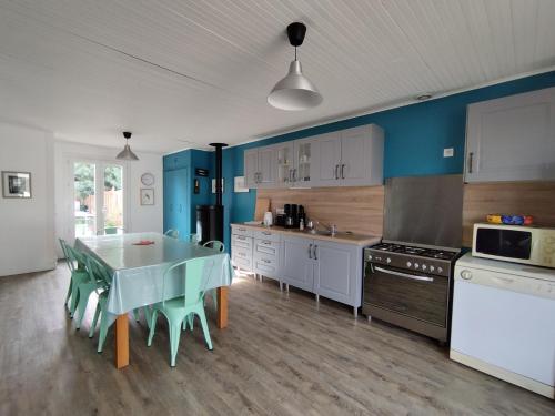 une cuisine avec une table et une cuisine aux murs bleus dans l'établissement A 150m de la plage, Maison moderne et spacieuse pour 7 personnes, à Les Sables Vignier