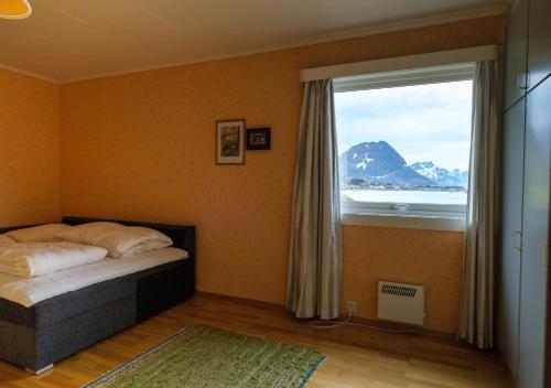 een slaapkamer met een bed en een groot raam bij Nordbo - unik plass med utsikt over Rambergstranda in Ramberg