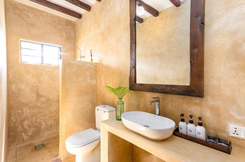 Poa Poa Bungalows في كيوينجوا: حمام مع حوض ومرحاض ومرآة