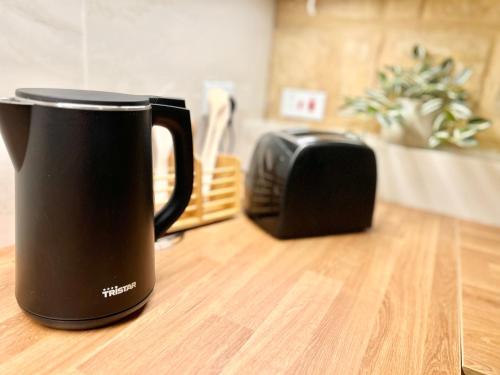 a black coffee mug sitting on a table next to a toaster at MCC St Rita in Il-Furjana