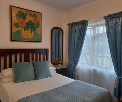 a bedroom with a bed with blue curtains and a window at Mountain View Holiday Home in Franskraal