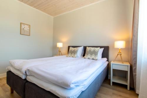 a bedroom with a large white bed with two lamps at Parkside Central Apartment by Kuus Sõlme in Kuressaare