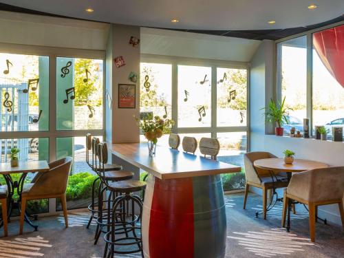 un restaurante con mesas, sillas y ventanas en ibis Bordeaux Pessac Route des Vins, en Pessac