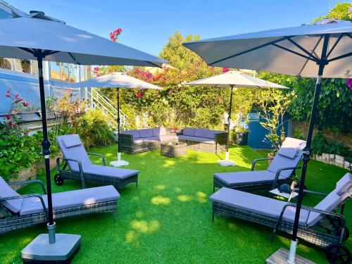 a patio with chairs and umbrellas on the grass at Hotel L'Escapade in Le Lavandou