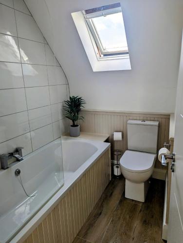 a bathroom with a tub and a toilet and a skylight at Sunny Cottage in Wexford