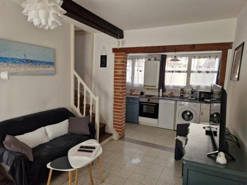 a living room with a couch and a kitchen at Romance en Baie de Somme in Saint-Valery-sur-Somme