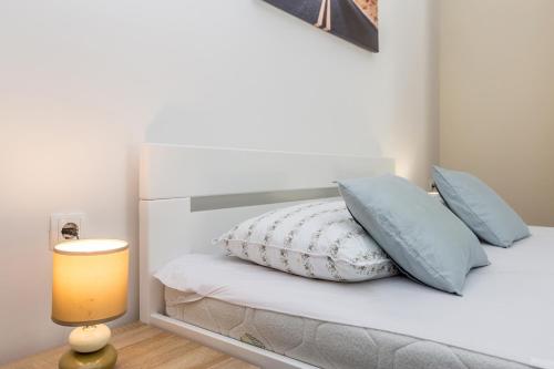 a bedroom with a bed with blue pillows and a lamp at Apartmani Tena in Njivice