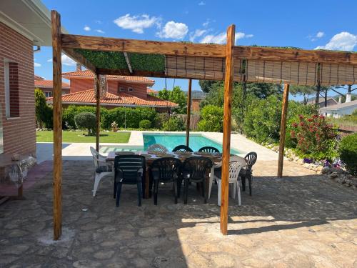 a patio with a table and chairs under a pergola at Gorriones in Pelayos de la Presa