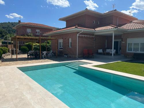 a house with a swimming pool in front of a house at Gorriones in Pelayos de la Presa