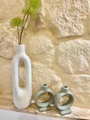 a white vase and three green vases next to a stone wall at MCC St Rita in Il-Furjana