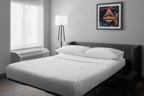 a bedroom with a bed with white sheets and a lamp at Hampton Inn Cleveland-Downtown in Cleveland
