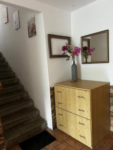 a staircase with a vase of flowers on top of a dresser at Restaurace a penzion Na Stráni in Klášterec nad Orlicí