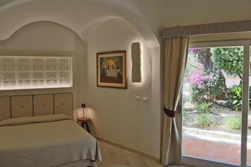 Corte Bianca - Adults Only & SPA - Bovis Hotels في كارديدو: غرفة نوم بسرير وباب زجاجي منزلق