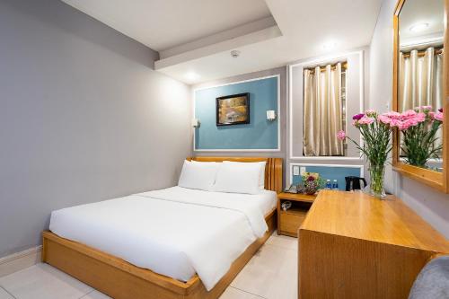 a bedroom with a bed and a table and flowers at Lucky Star Hotel - Bui Vien Walking Street in Ho Chi Minh City