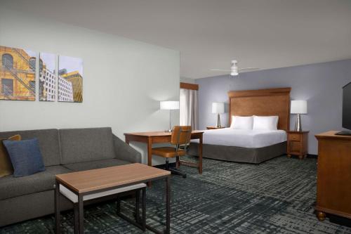 ein Hotelzimmer mit einem Bett, einem Sofa und einem Schreibtisch in der Unterkunft Homewood Suites by Hilton Omaha - Downtown in Omaha
