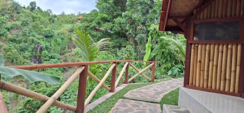 a wooden walkway next to a building with a forest at Uma Nirmala Aling-Aling in Singaraja